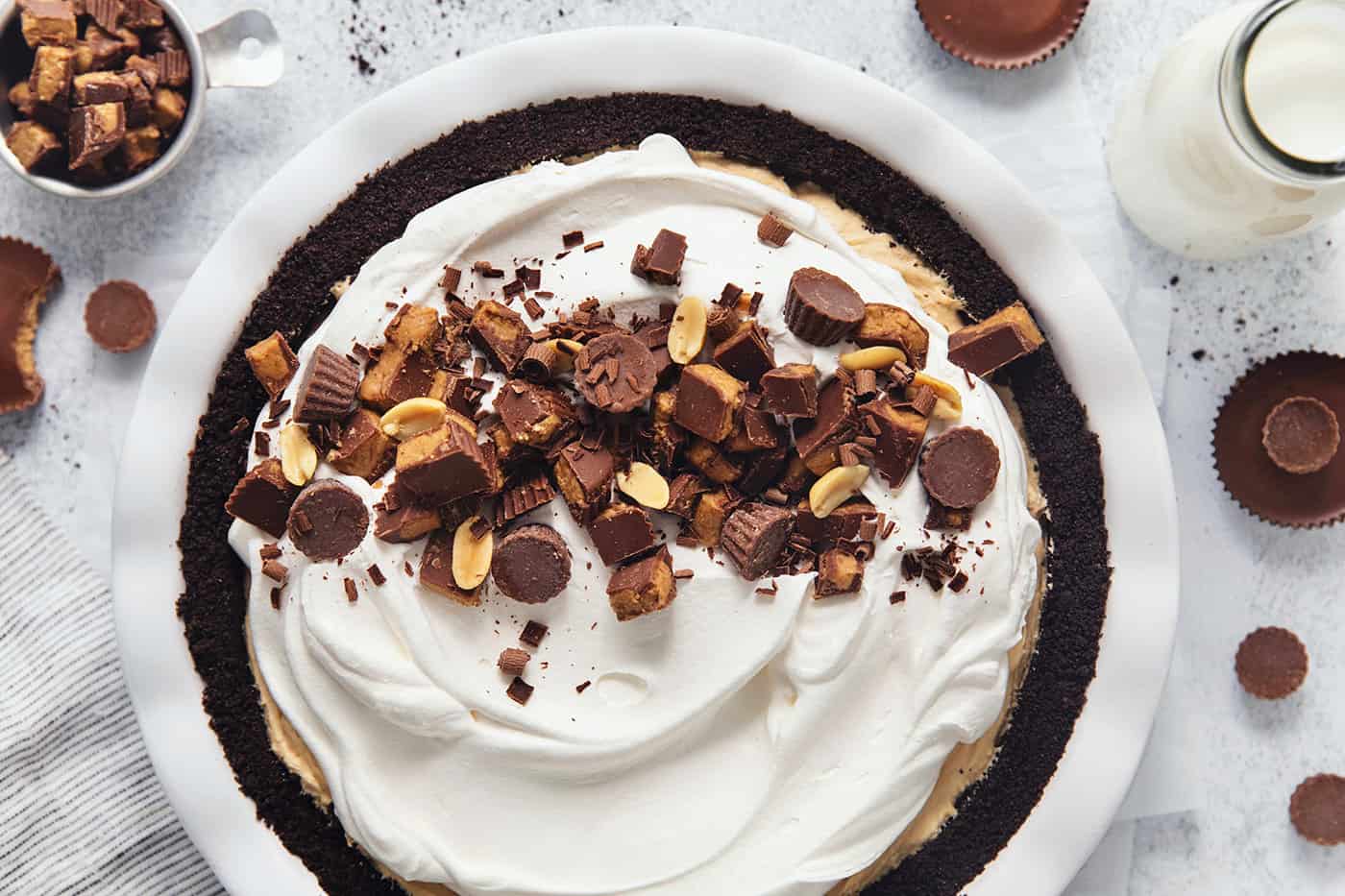 A Reeses pie is shown with half of it topped with chopped peanut butter cups.