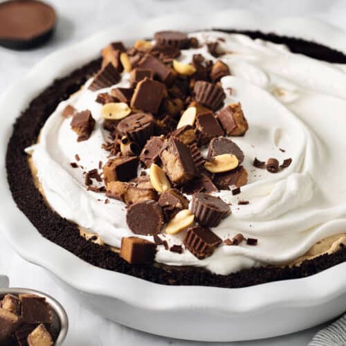 A Reeses pie is shown with half of it topped with chopped peanut butter cups.