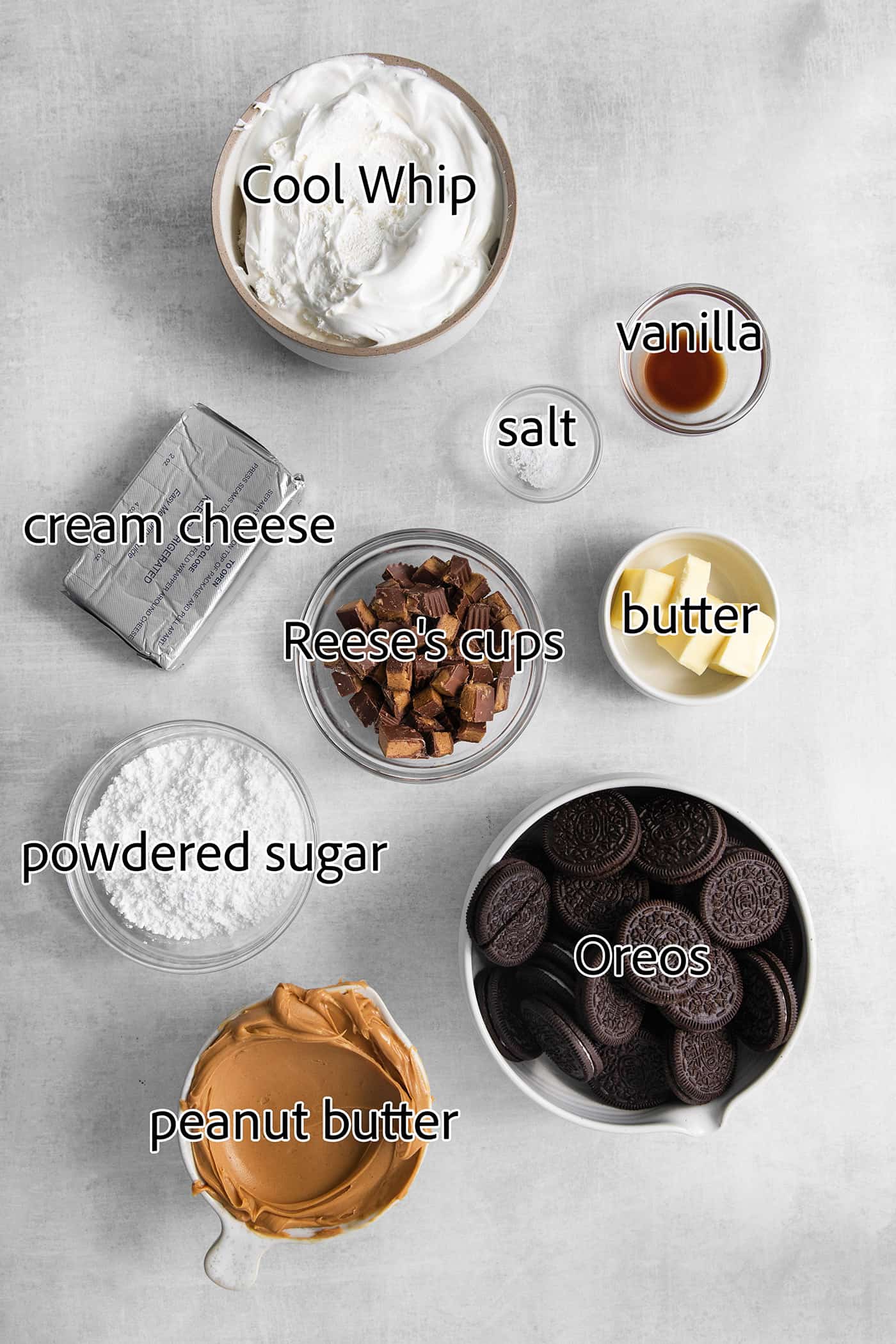 The ingredients for Reeses pie are shown: peanut butter, cream cheese, peanut butter cups, whipped topping, butter, Oreos, salt, vanilla, powdered sugar.