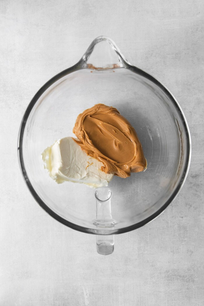 Cream cheese and peanut butter are added to a glass bowl.