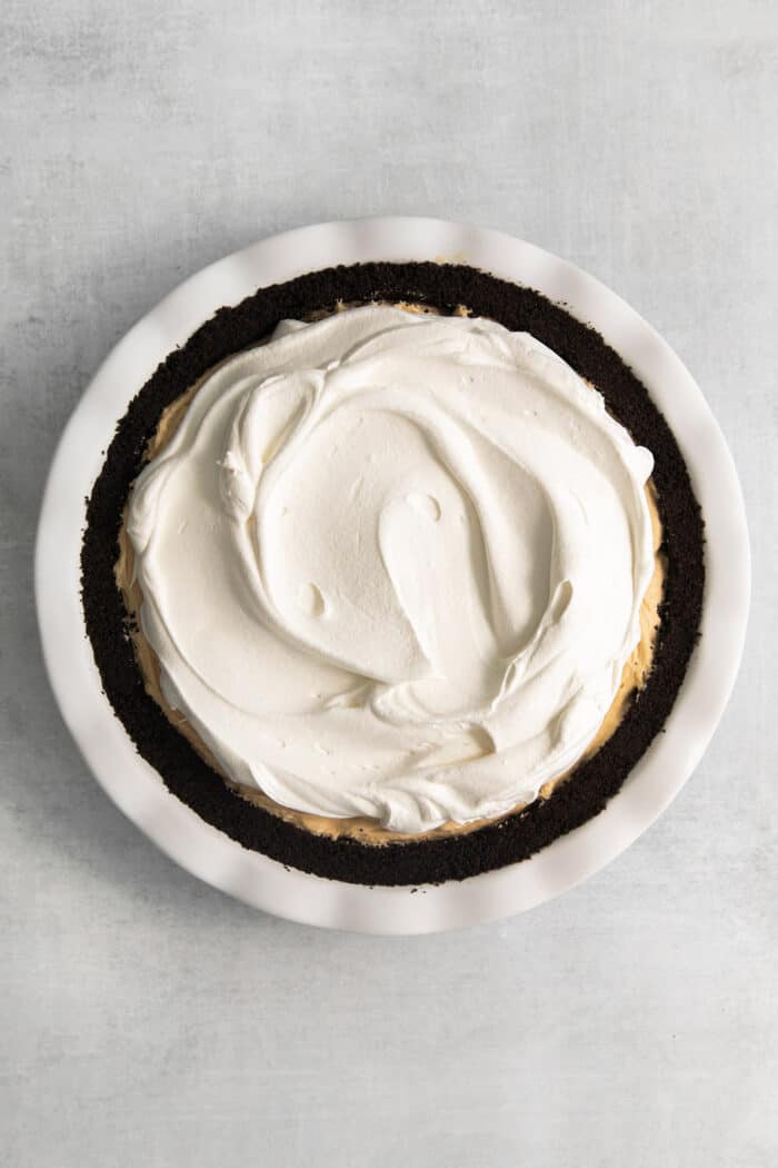 Whipped topping is spread across the surface of the pie.