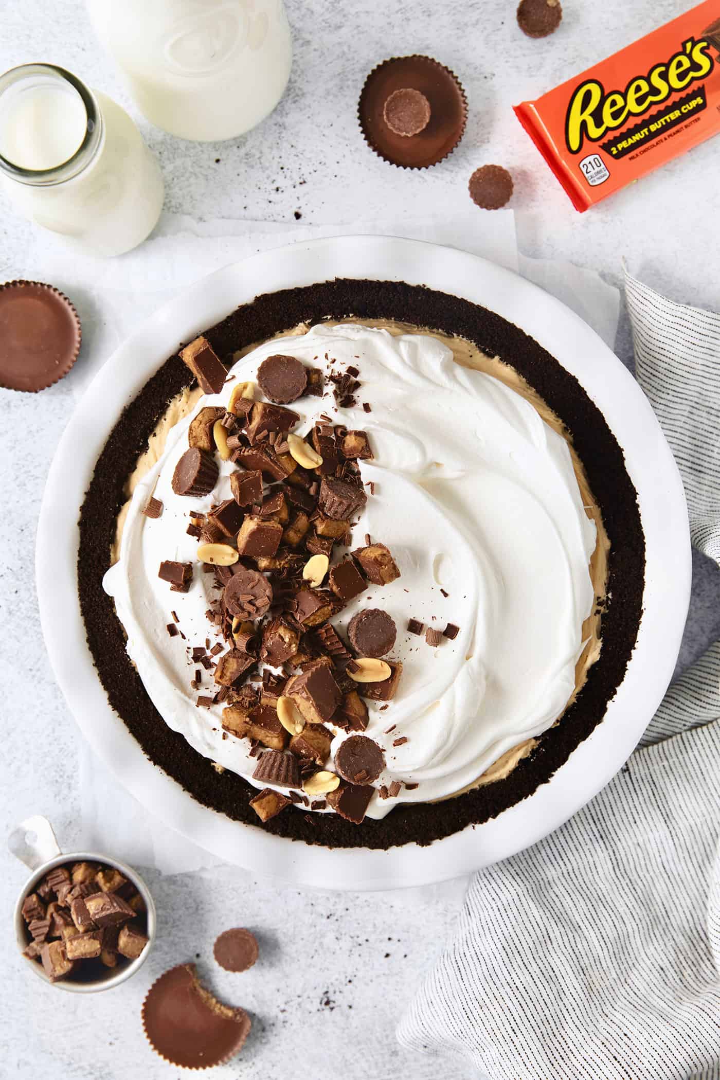 A whole Reeses pie on a white background with a package of peanut butter cups.