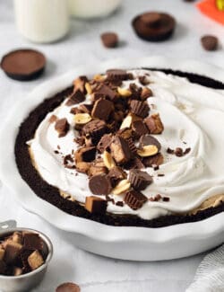 A Reeses pie topped with whipped topping and chopped peanut butter cups.