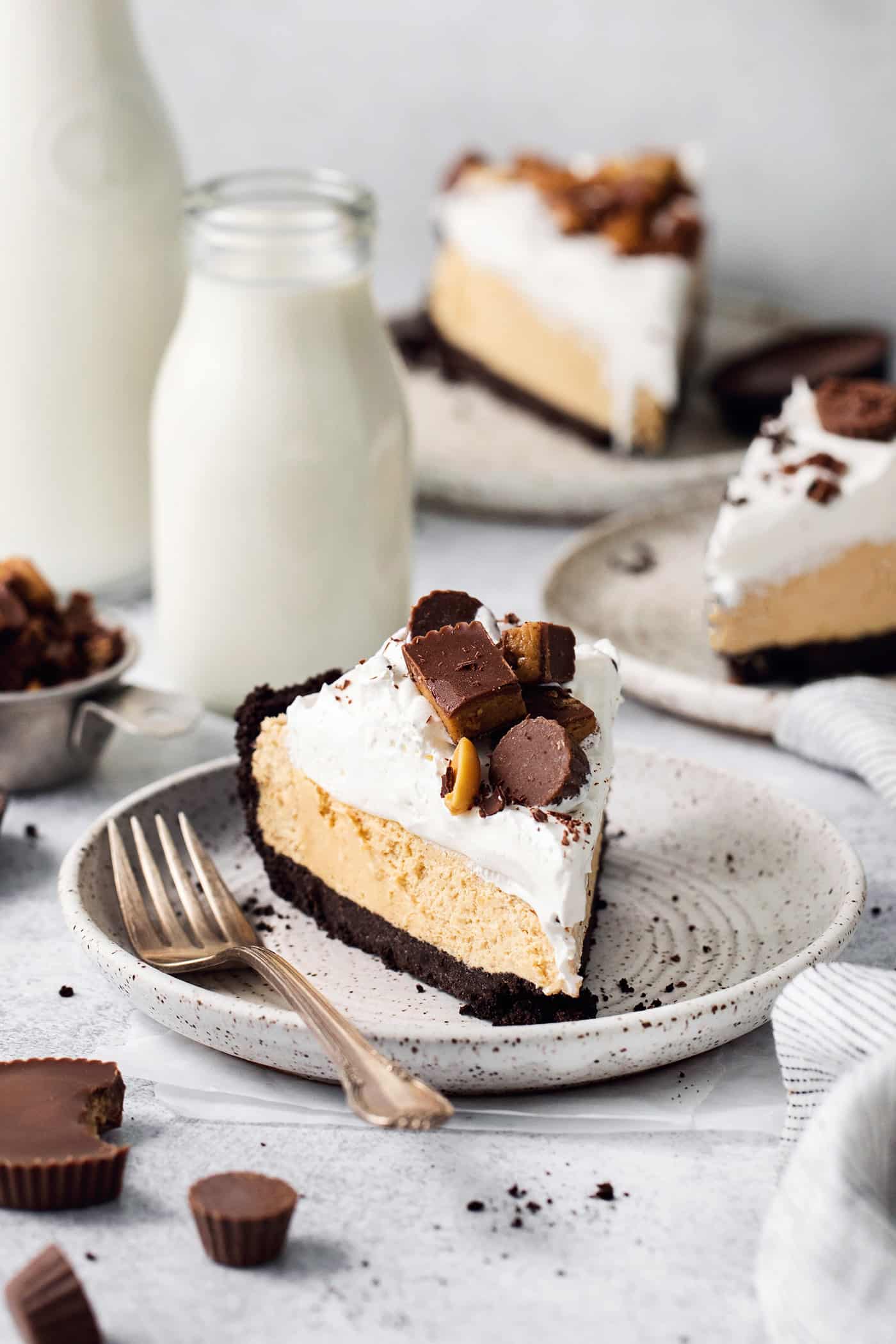 A candy-topped piece of Reeses pie is shown on a plate with more slices of pie around it.