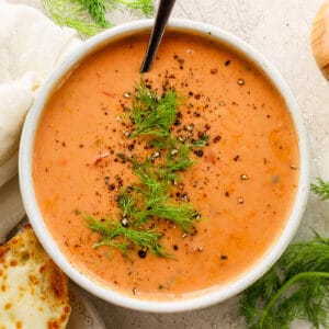 overhead photo of a white bowl with creamy tomato soup