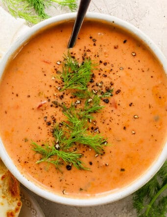 overhead photo of a white bowl with creamy tomato soup