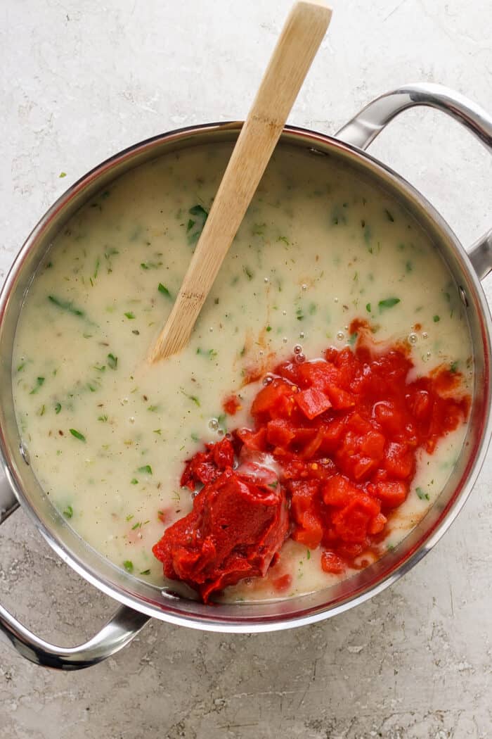 Diced tomatoes are added into the pot for tomato bisque.