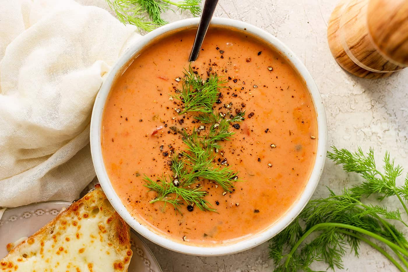 a bowl of tomato bisque with chopped dill over the top