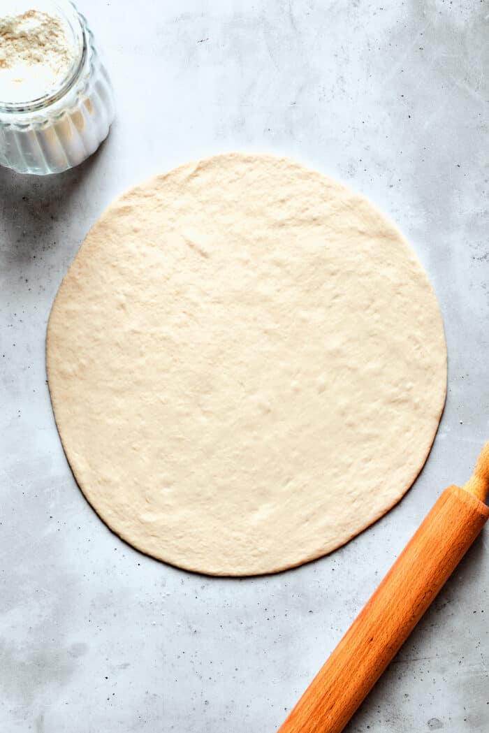 A circle of pizza dough is rolled out.
