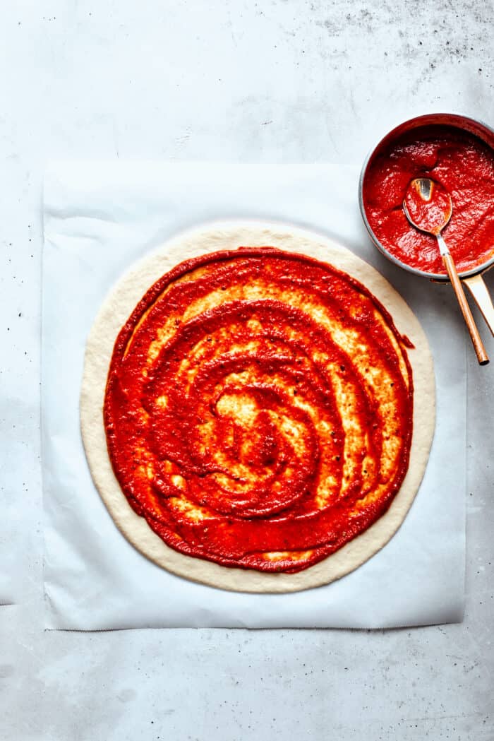Pizza sauce is spread over the dough.