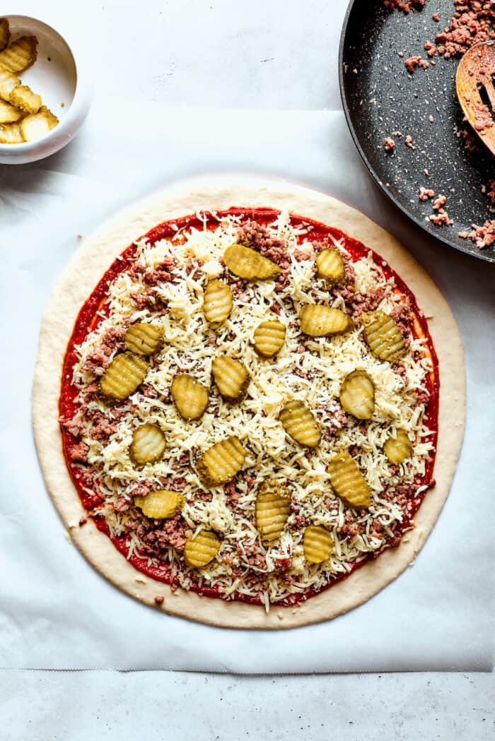 Pickles are added to the pizza.