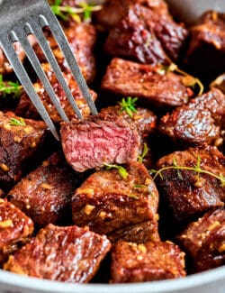 cubes of ribeye steak cooked in garlic butter, in a skillet