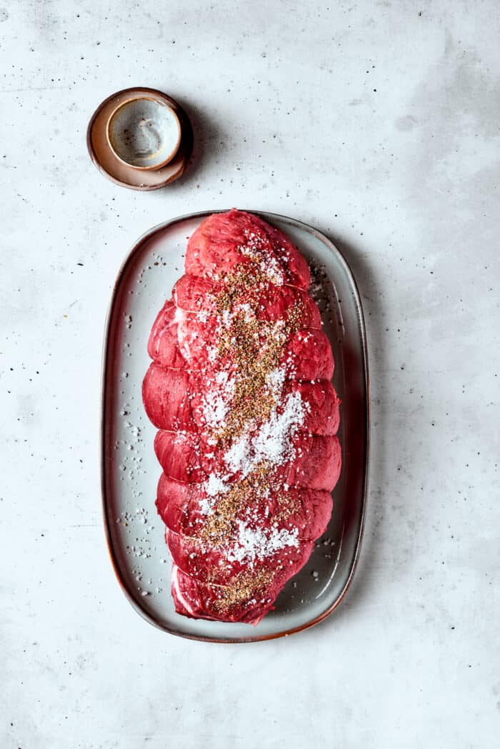 Salt and pepper are used to season a sirloin tip roast.