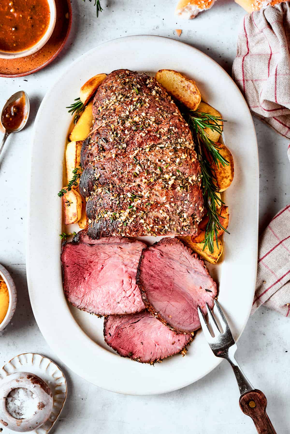 A white platter holds a sirloin tip roast with three slices cut from it.