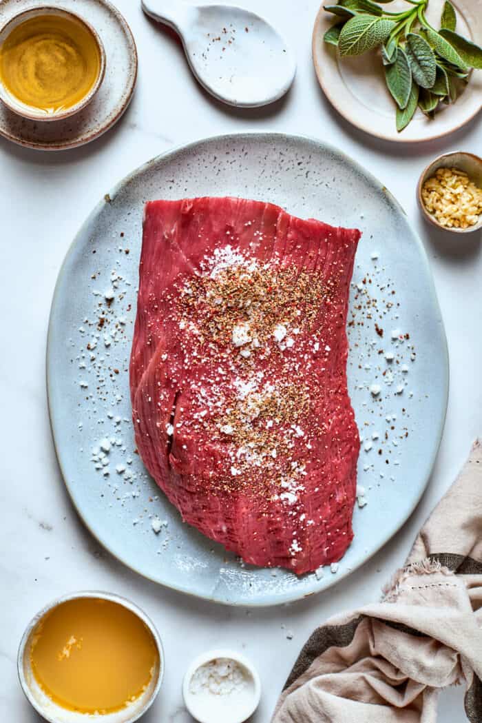 A piece of top round roast is seasoned with salt and pepper.