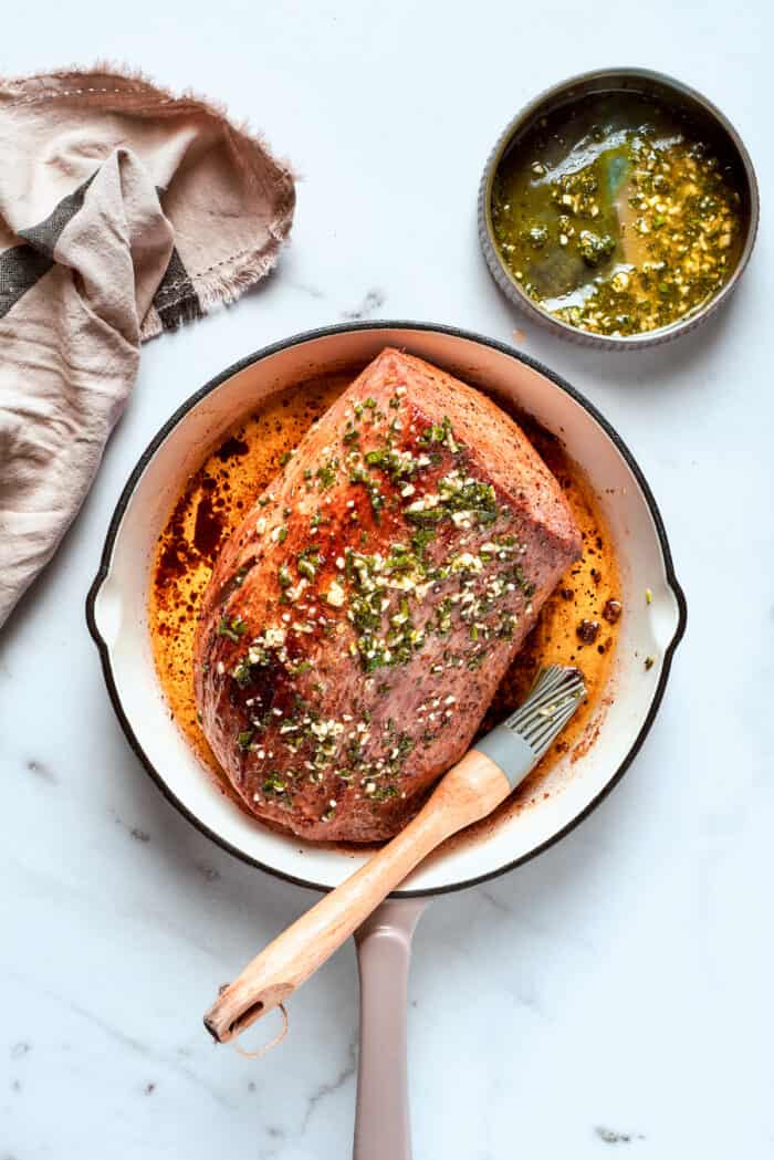 The roast is topped with herbs and seared.