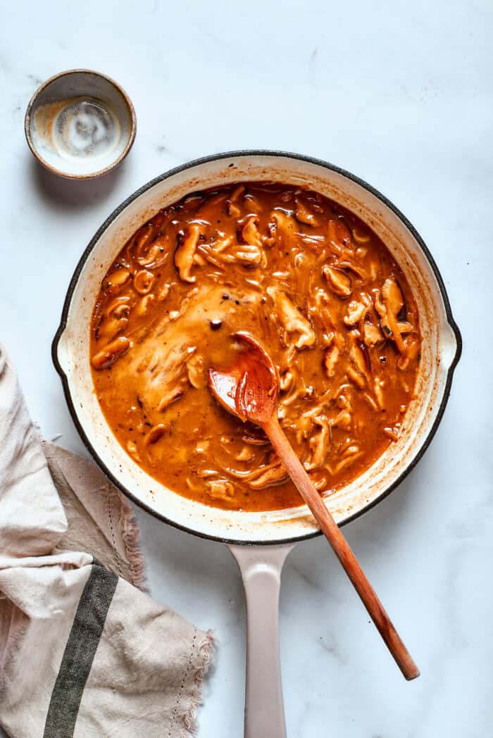 A wooden spoon stirs the gravy.