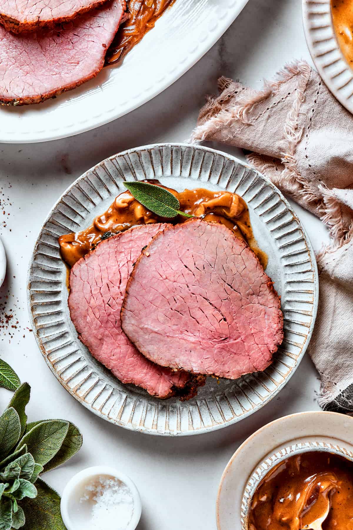 Two slices of top round roast with gravy are served on a plate.