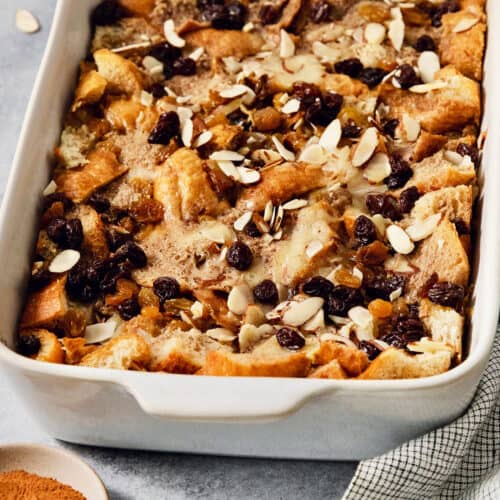 A baking dish full of capirotada topped with raisins and almonds.