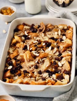 A baking dish full of capirotada topped with raisins and almonds.