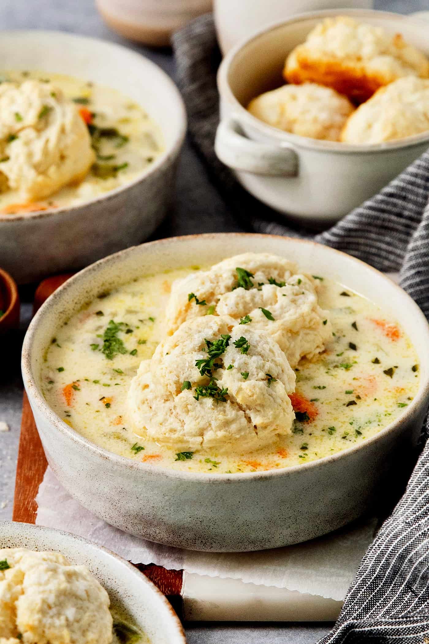 Bowls of biscuit-topped chicken pot pie soup with a basket of biscuits behind them.