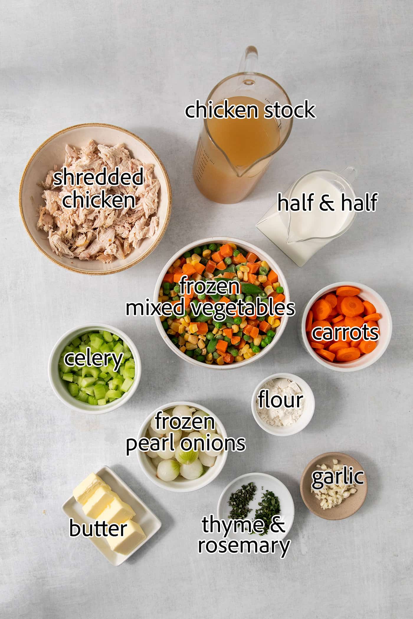 Chicken pot pie soup ingredients are shown portioned out: carrots, celery, chicken, flour, half and half, broth, frozen onions, frozen vegetables, salt, garlic, butter.