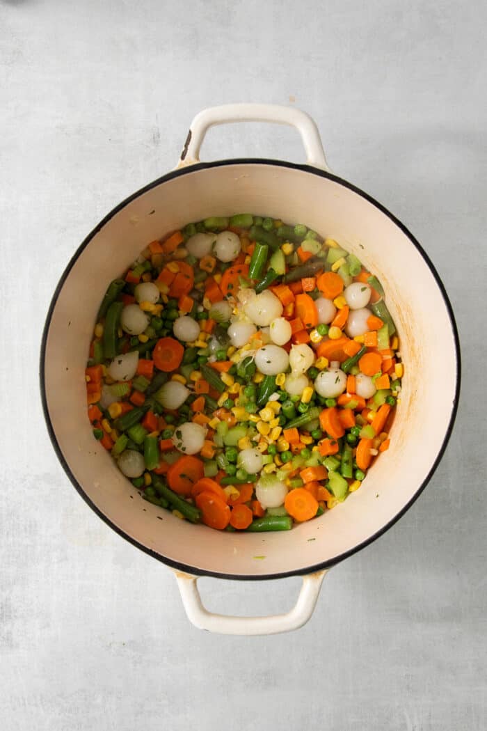 The vegetables are added to the broth in a pot.