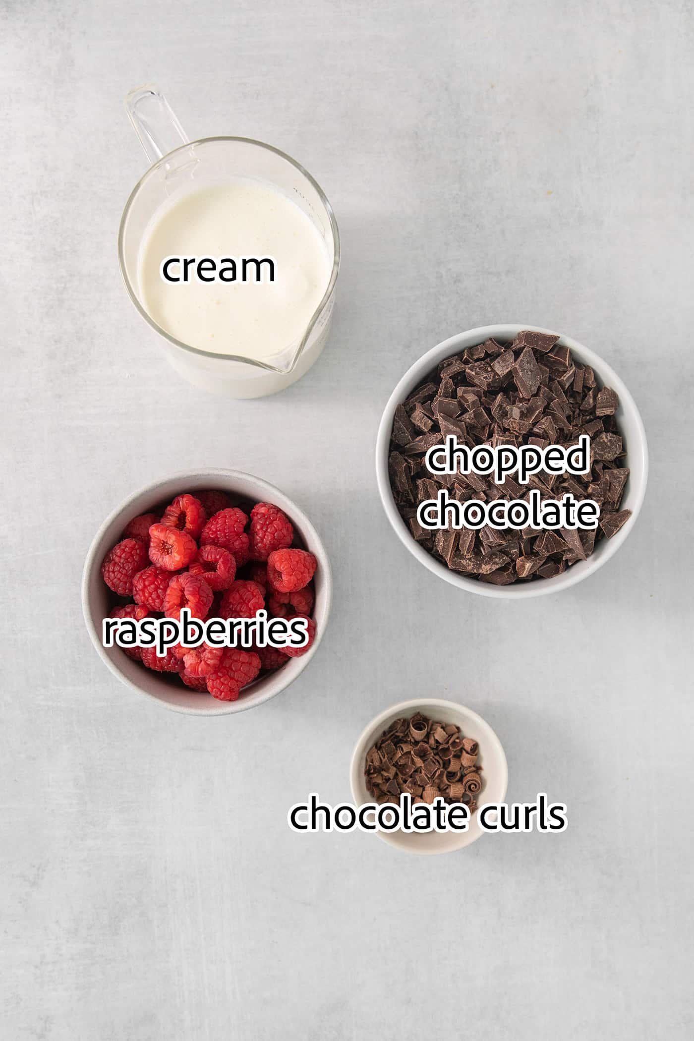 ingredients for chocolate ganache, plus chocolate curls and raspberries for garnish