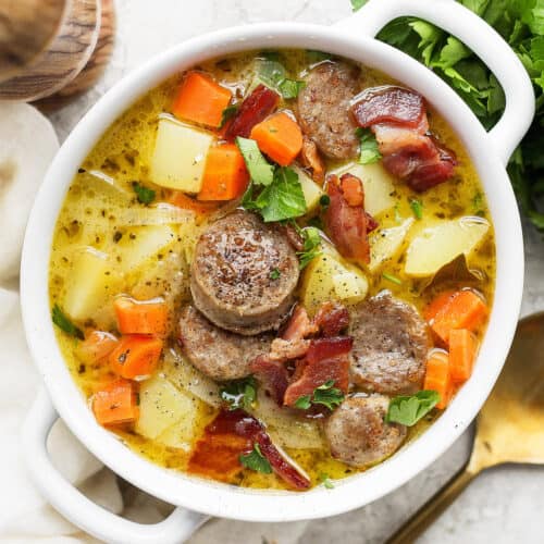 A white handled bowl with a serving of German potato soup.