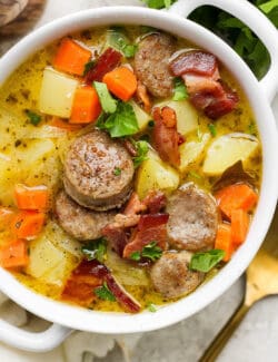 A white handled bowl with a serving of German potato soup.