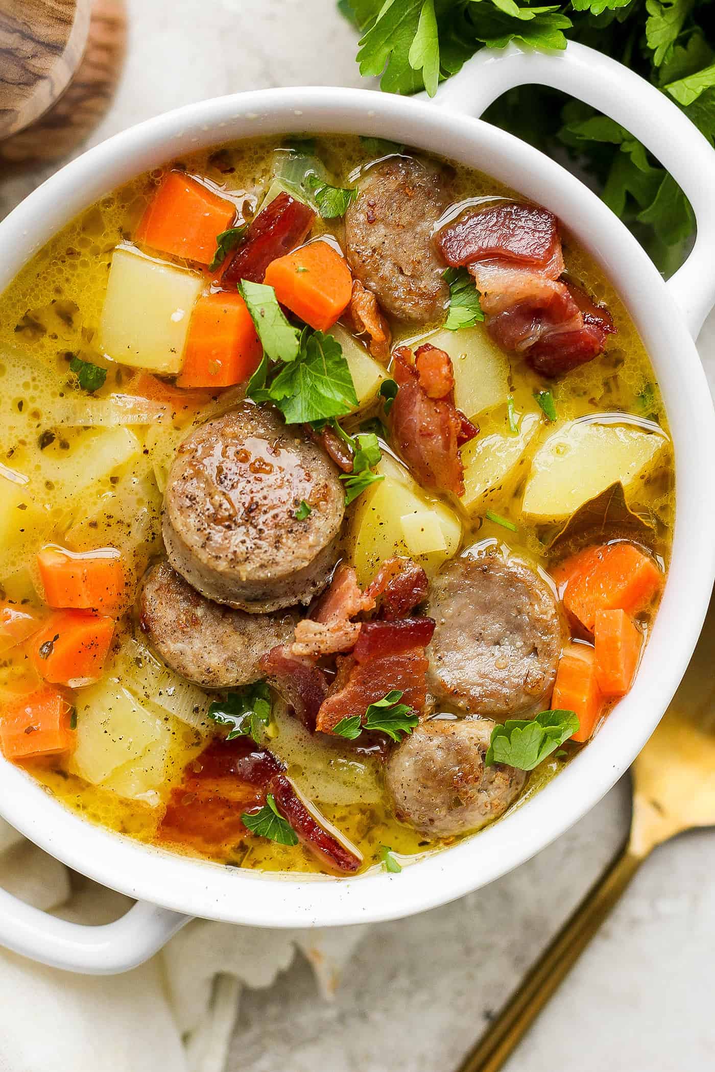 A white handled bowl with a serving of German potato soup.