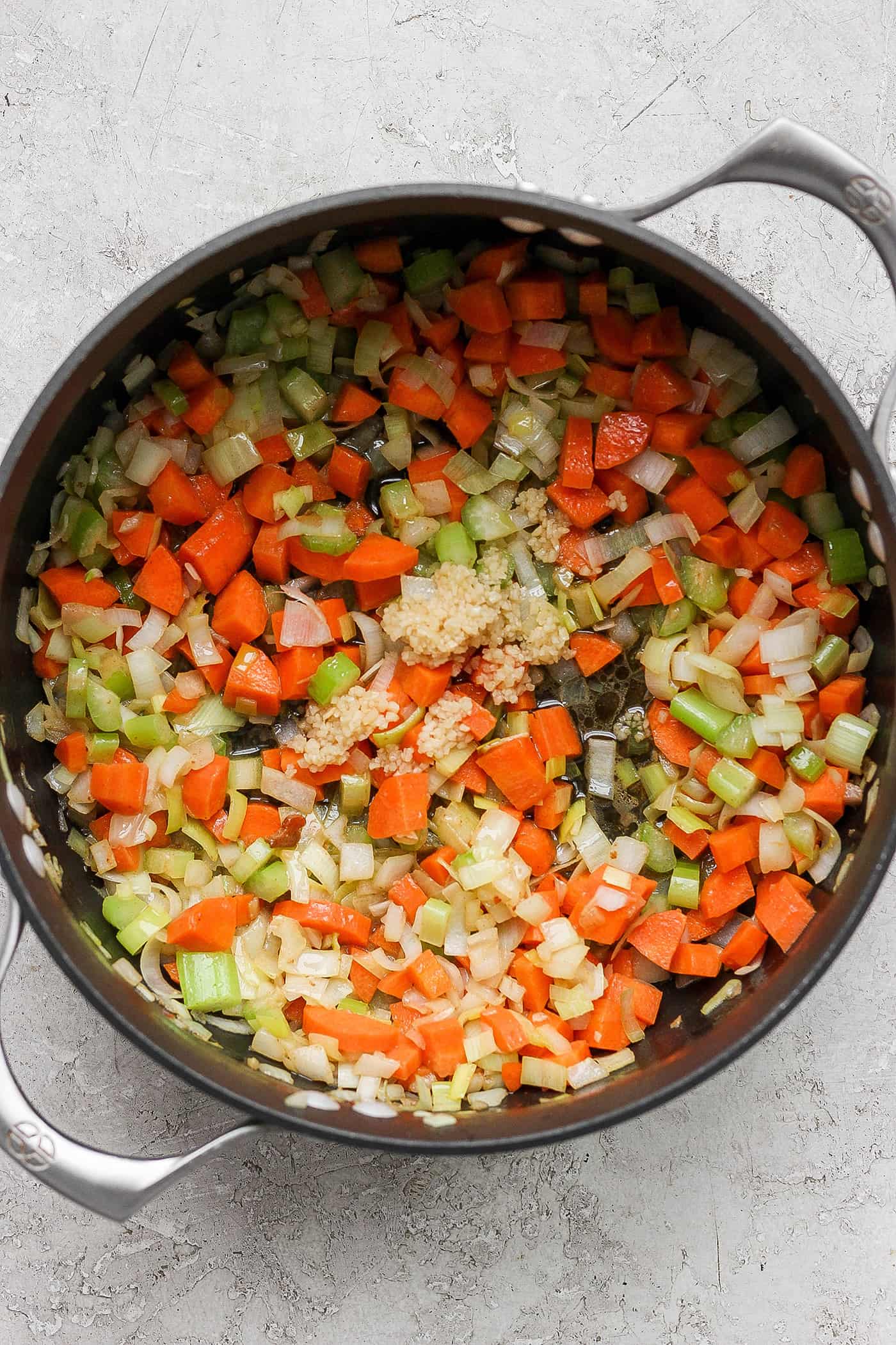 This German Potato Soup recipe is packed with savory sausage, salty bacon, and plenty of vegetables plus a spoonful of half-and-half. The carrots, celery, leek, onion, and garlic cook down in the cast iron pan.