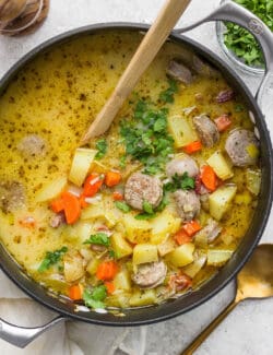 A wooden spoon stirs a pot of German potato soup.