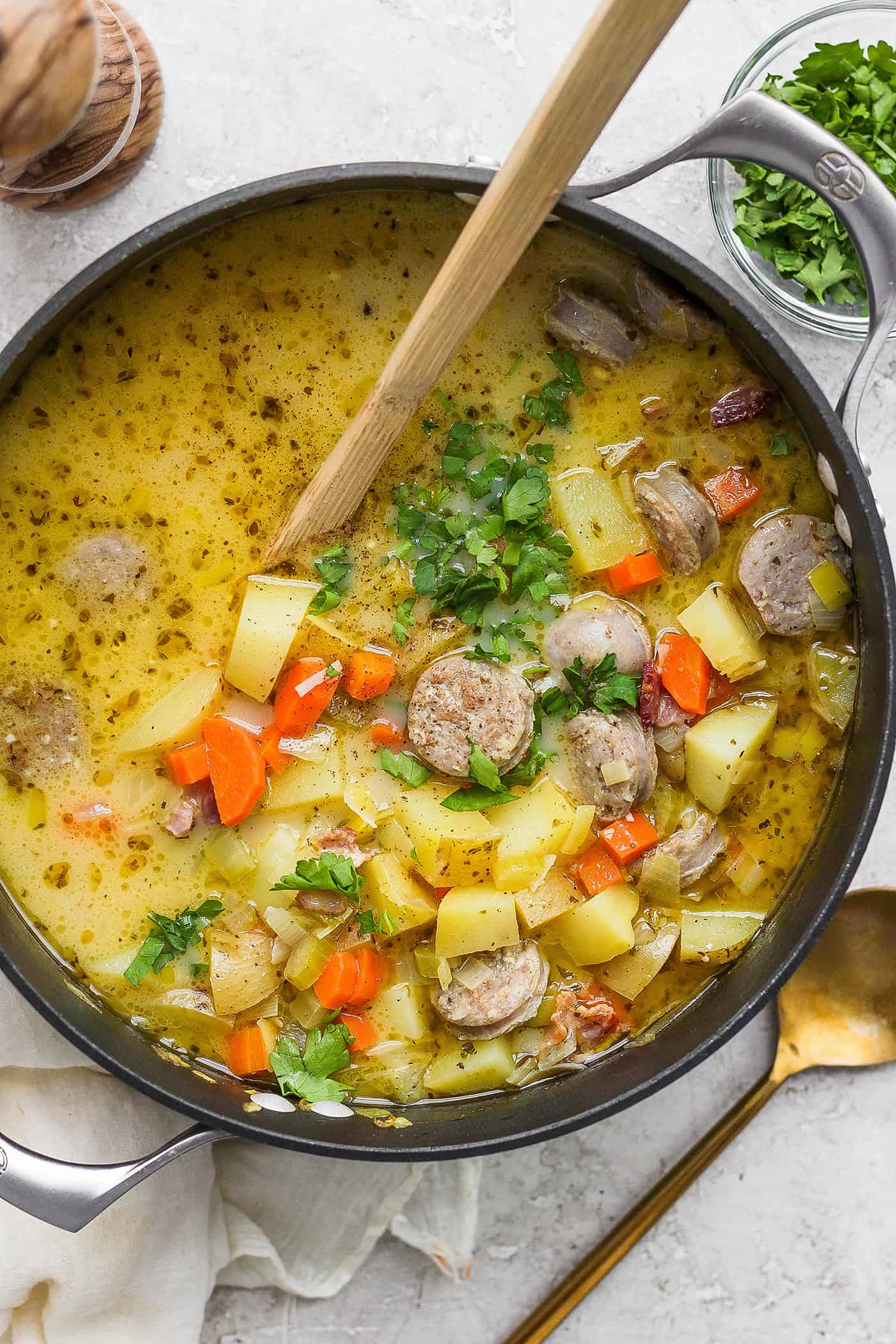 A wooden spoon stirs a pot of German potato soup.