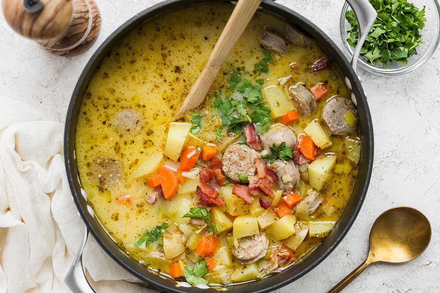 A wooden spoon stirs a pot of German potato soup.