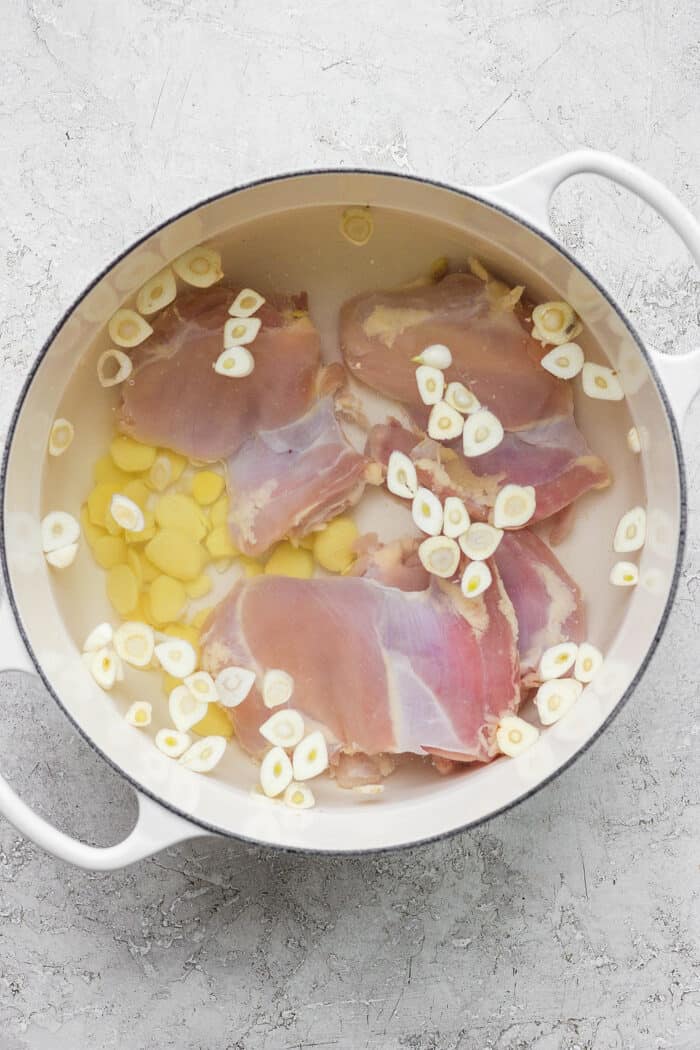 Chicken thighs cook in water with garlic and ginger.