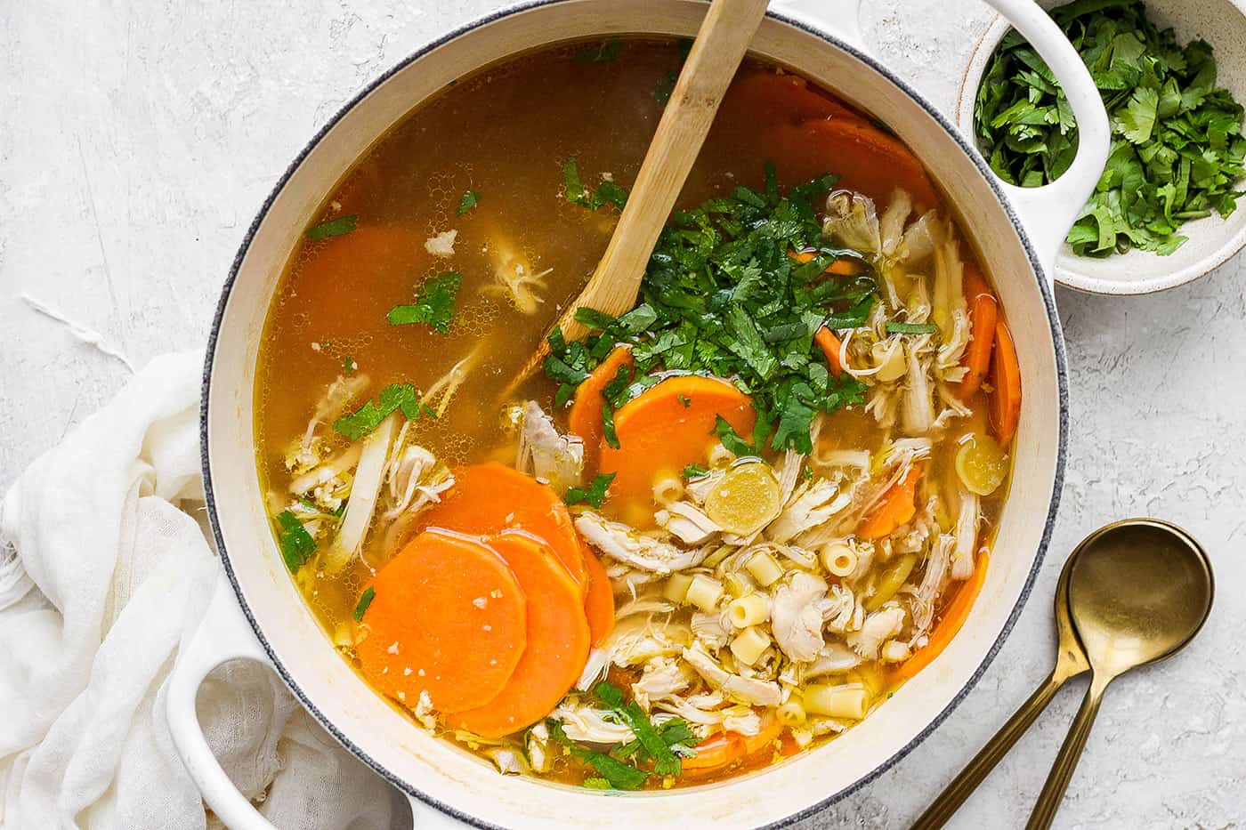 A spoon stirs a pot of ginger chicken soup.