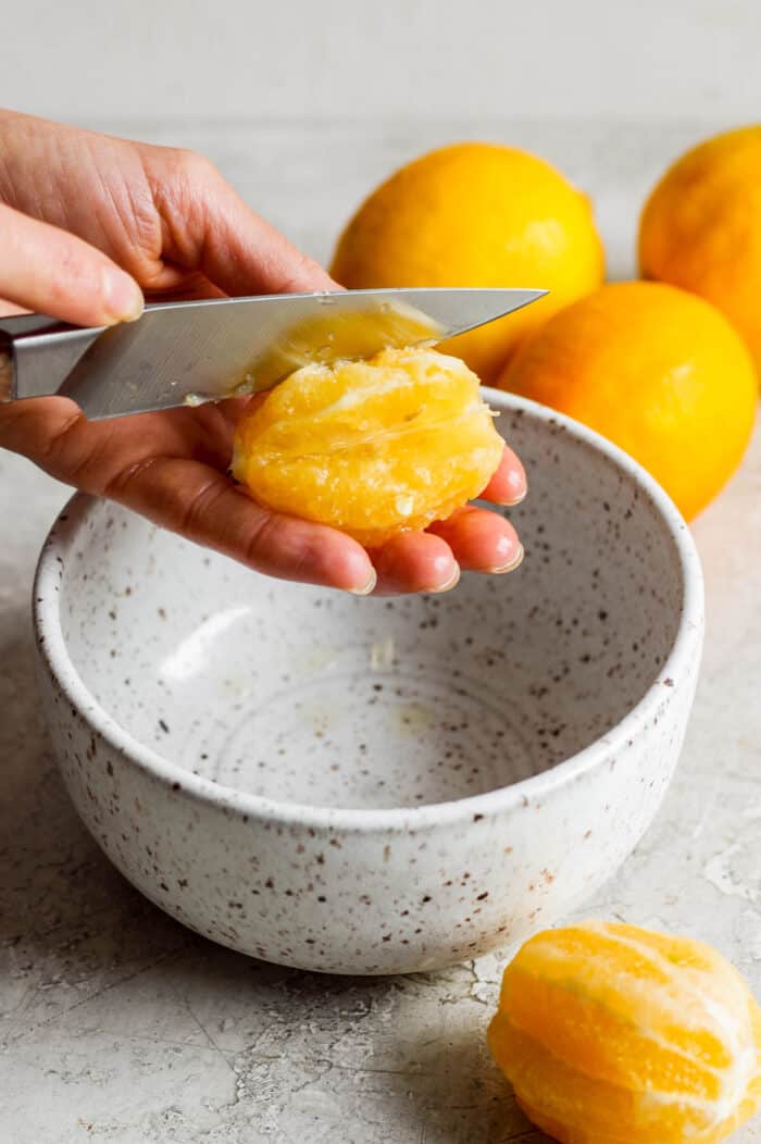 A knife scrapes out a segment of Meyer lemon.