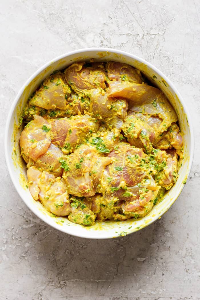 Chicken marinates in a bowl.