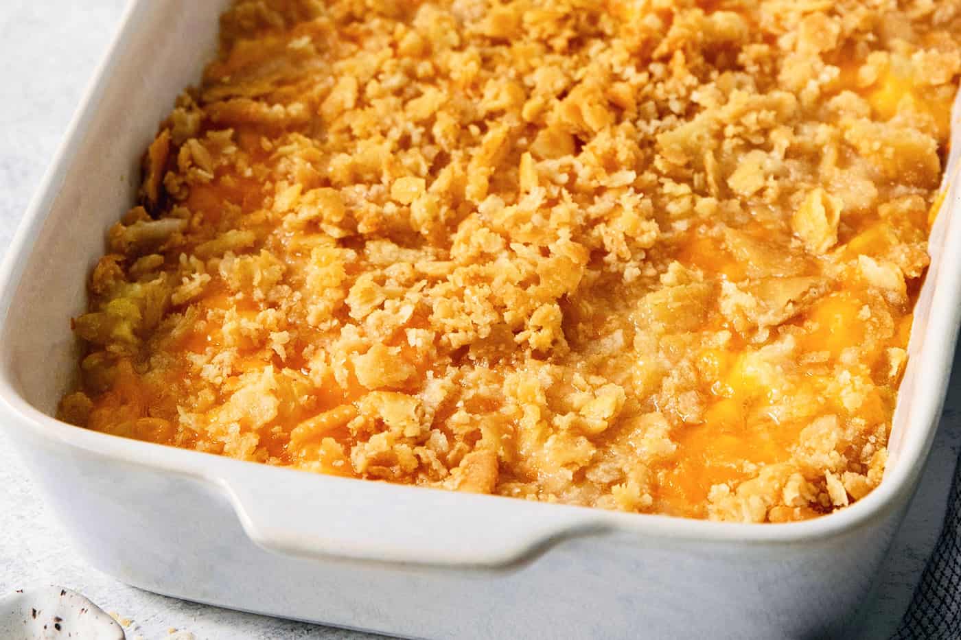 A white baking dish holds cracker-topped pineapple casserole.