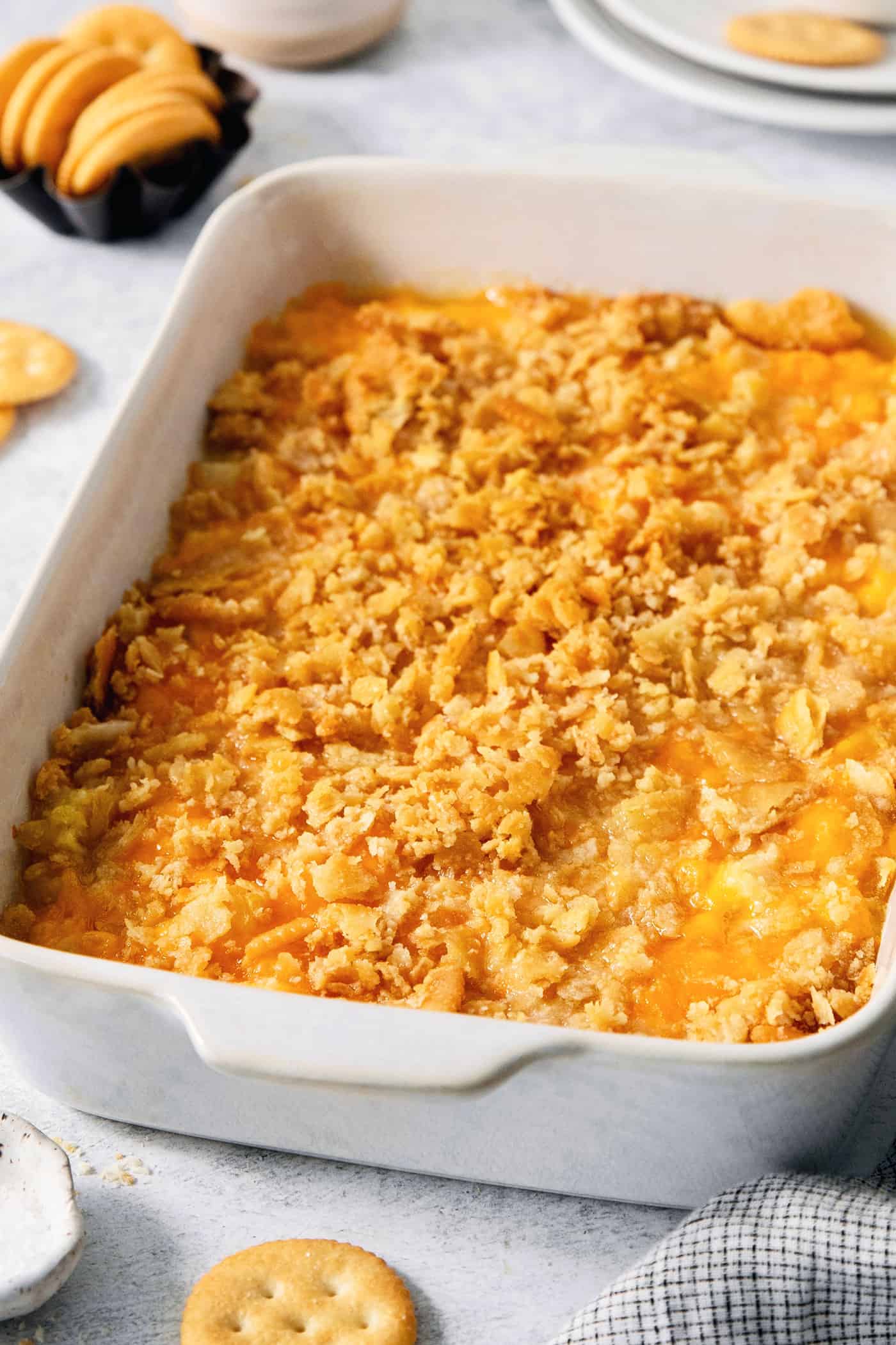 A white baking dish holds cracker-topped pineapple casserole.