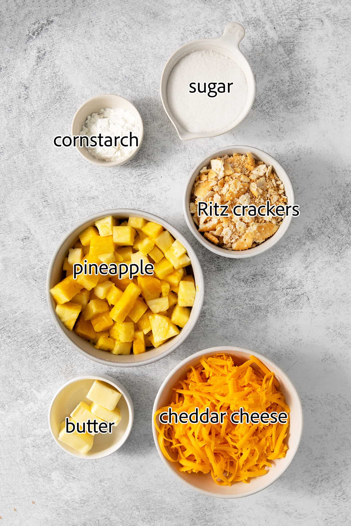 Ingredients needed to make pineapple casserole are shown: pineapple, cornstarch, butter, ritz crackers, cheddar cheese, sugar.