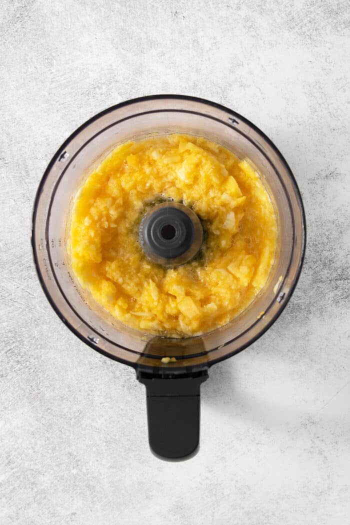 Pineapple chunks are added to a food processor.