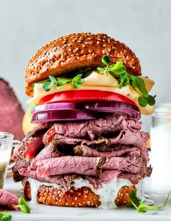 roast beef, cheese, onion, and tomato layered on a sesame seed bun