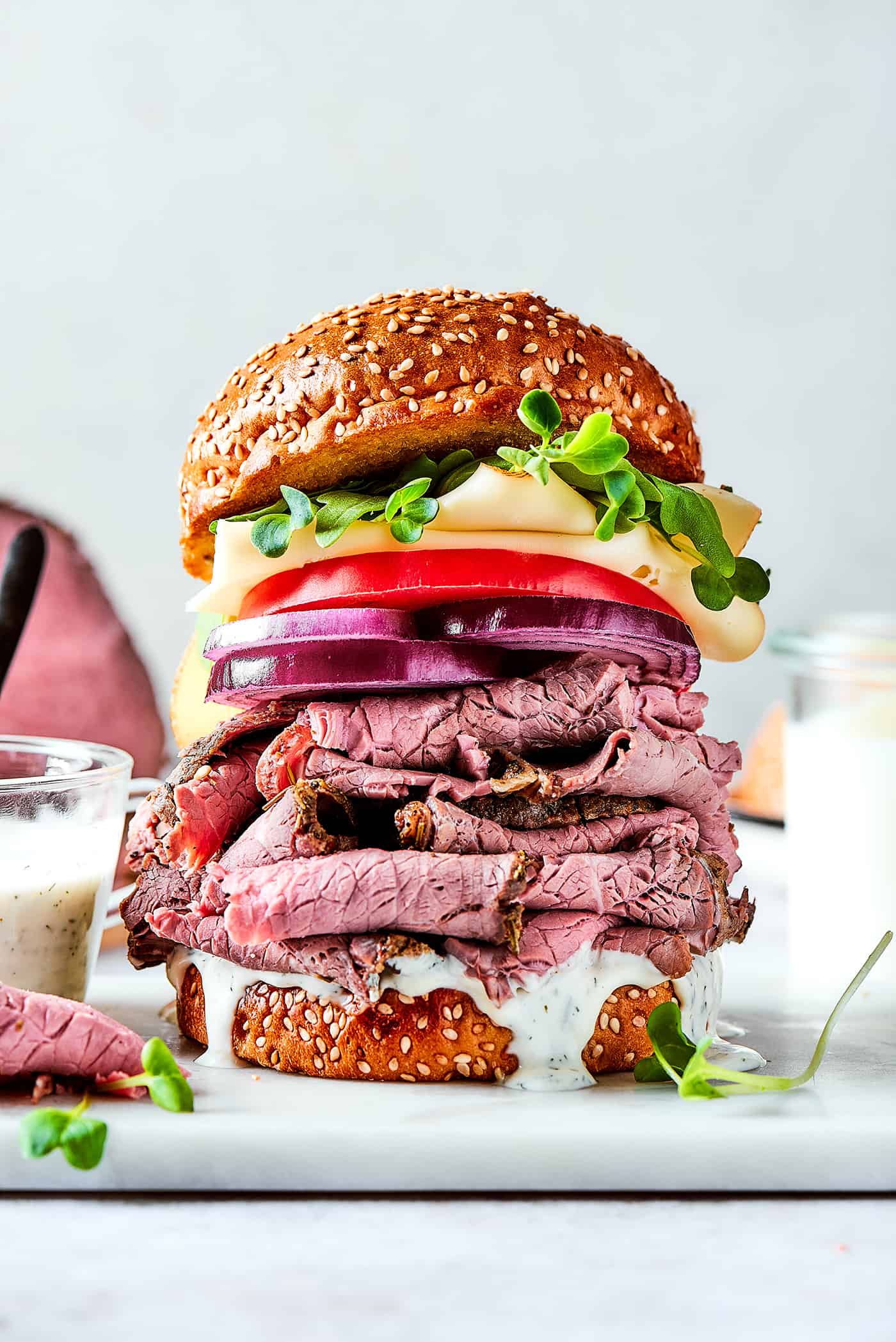 layers of roast beef, cheese, onion, and tomato on a sesame seed bun