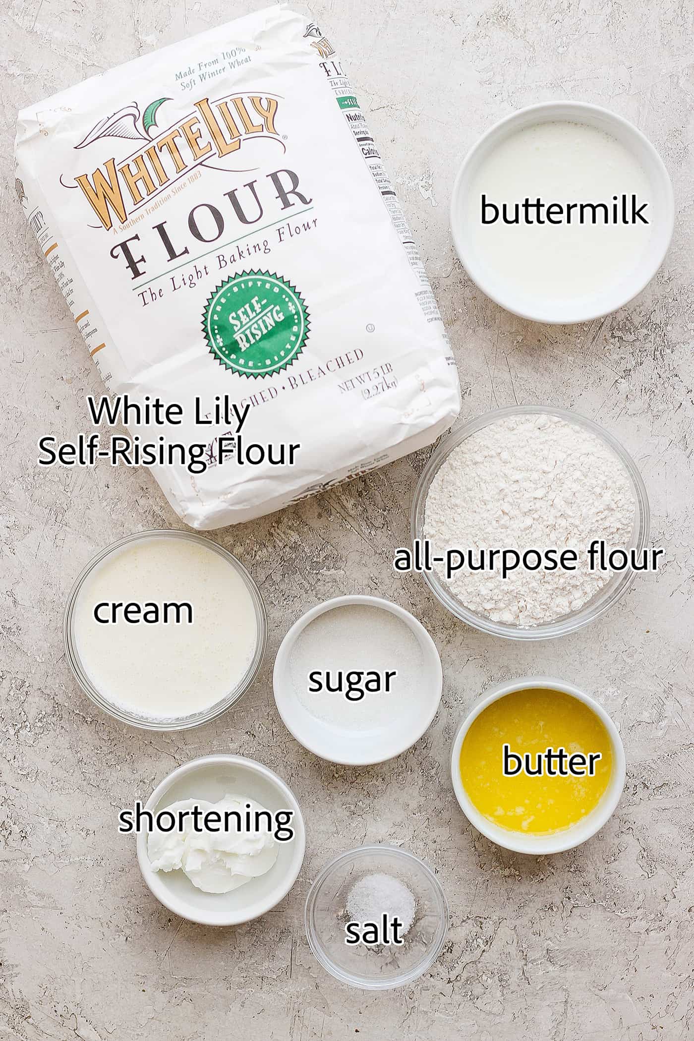 The ingredients needed to make touch of grace biscuits are shown: White Lily flour, butter, flour, sgar, cream, shortening, buttermilk, salt.