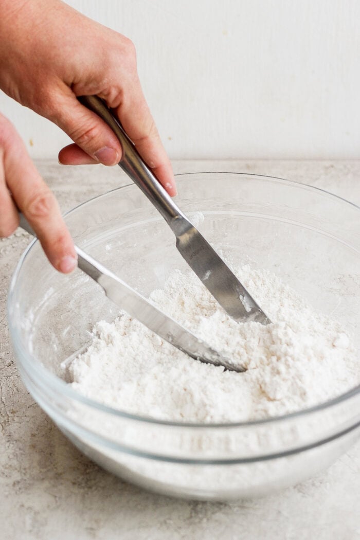 Hands use mixing utensils to mix the biscuit dough.