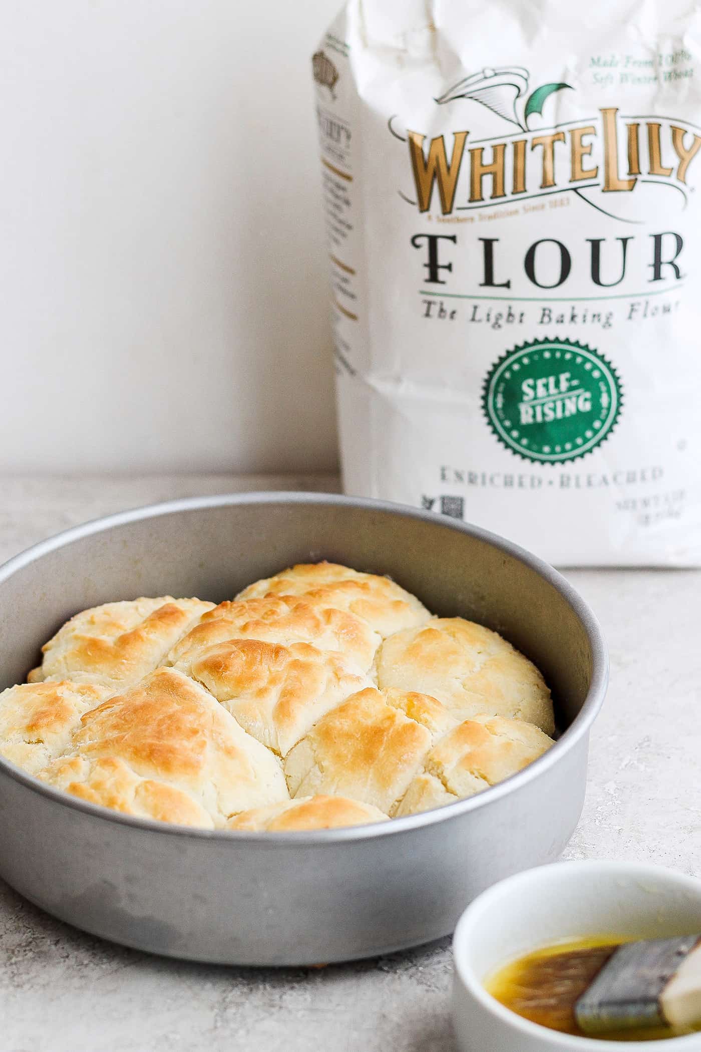 A bag of White Lily flour is seen in the background with baked touch of grace biscuits in a baking tin in the foreground.