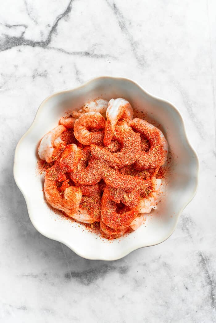 Seasoning shrimp in a bowl for cajun shrimp pasta.
