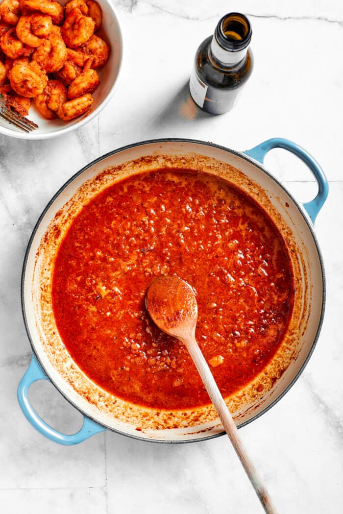 A spoon stirs the spiced sauce for cajun shrimp asta.